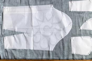 top view of paper pattern layout of dress on gray fabric on table at home