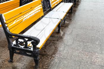 yellow wooden bench covered by snow on Manezhnaya square in Moscow city in winter