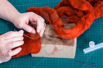 master class of repairing fleece glove using Needle felting process - above view of craftsman mixes fibers in felt with felting needle