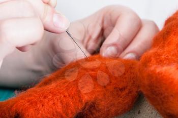 master class of repairing fleece glove using Needle felting process - craftsman binds felted cloth with felting needle close up