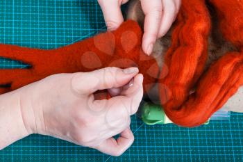 master class of repairing fleece glove using Needle felting process - top view of craftsman binding fibers in glove with felting needle