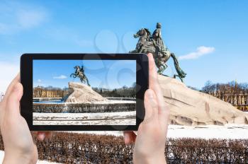 travel concept - tourist photographs of Bronze Horseman monument of Peter the Great in the Senate Square in Saint Petersburg in Russia on smartphone in spring