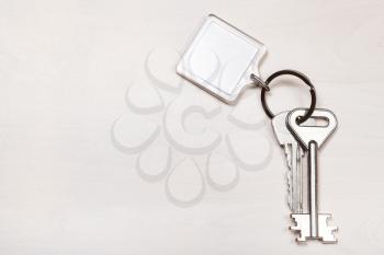 bundle of keys on keyring with blank white keychain on pale brown table