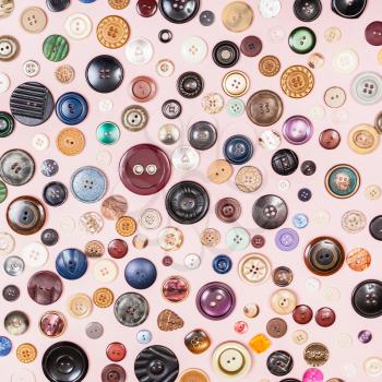 top view of many various buttons on pink background