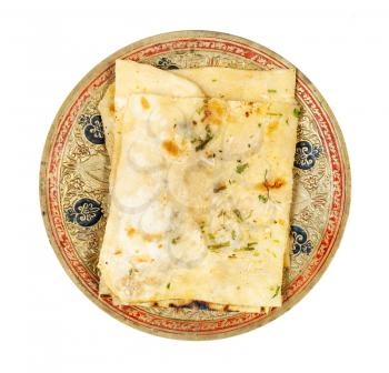 Indian cuisine - top view of garlic naan (garlicky flatbread) on brass plate isolated on white background