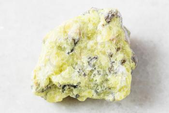 closeup of sample of natural mineral from geological collection - unpolished native Sulphur (Sulfur) rock on white marble background from Vodinskoye deposit, Samara region, Russia