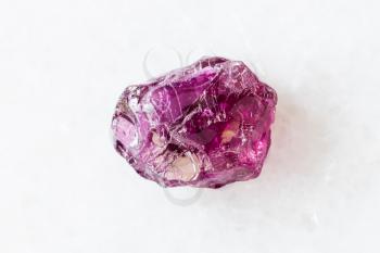 closeup of sample of natural mineral from geological collection - rough Rhodolite (pyrope garnet) crystal on white marble background from Lokirima, Lodwar, Turkana dist, Riffvalley prov, Kenya