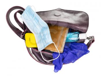 top view of woman's bag with protective mask, sanitizer, gloves, wallet and smartphone isolated on white background