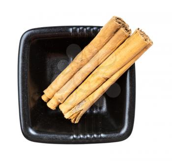 top view of two sticks of continental ceylon cinnamon in black bowl isolated on white background