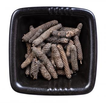 top view of java long pepper in black bowl isolated on white background