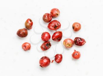 several pink peppercorns (Baie rose) close up on gray ceramic plate