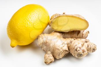 natural fresh whole and cut ginger roots and whole lemon fruit on gray plate close up