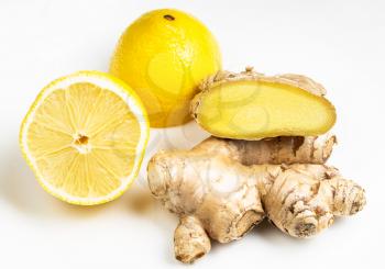 natural fresh whole and cut ginger roots and cross-cut lemon fruit on gray plate close up