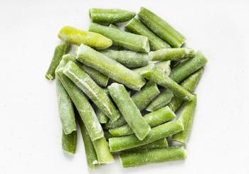 pile of cut and frozen green beans close up on gray ceramic plate