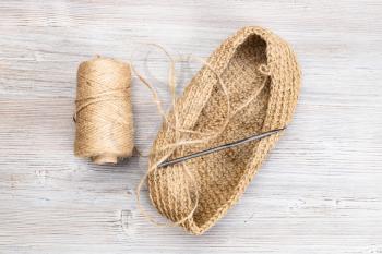 top view of spool of hemp twine, hand-knitted bottom of bag and crochet on wooden table