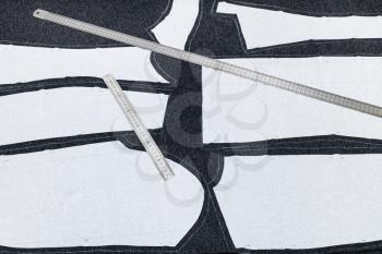 layout of sewing patterns of dress and steel rulers on dark fabric