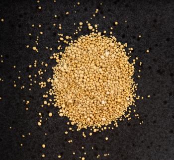 top view of pile of granulated dried yeast close up on black ceramic plate