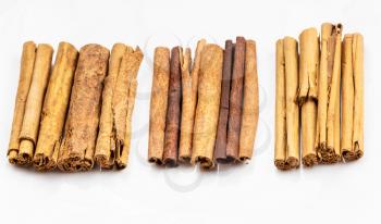 different cinnamon sticks (alba premium ceylon, chinese cassia and continental ceylon cinnamon) on white plate