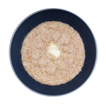 top view of buttered porridge from wheat groats (crushed partly hulled wheat grains) in gray bowl isolated on white background