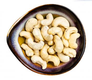 top view of raw cashew seeds in ceramic bowl isolated on white background