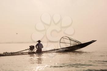 Myanmar travel attraction landmark - Traditional Burmese fisherman with fishing net at Inle lake in speeding motor boat
