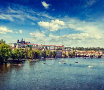 Vintage retro hipster style travel image of  Vltava river and Gradchany (Prague Castle) and St. Vitus Cathedral and Charles bridge an people in paddle boats in the Prague, Czech Republic with grunge t