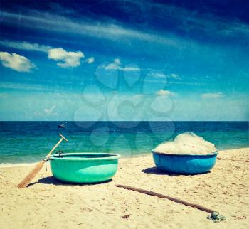 Vintage retro hipster style travel image of fishing coracle boats on beach with grunge texture overlaid. Mui Ne, Vietnam