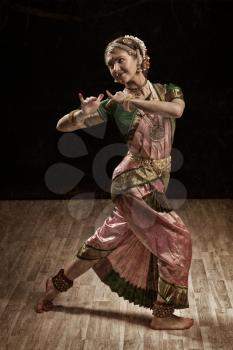 Vintage retro style image of young beautiful woman dancer exponent of Indian classical dance Bharatanatyam in Krishna pose