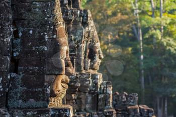 Ancient stone faces of Bayon temple, Angkor, Cambodia on sunset