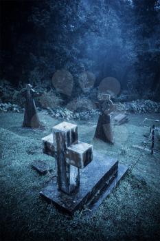 Spooky Halloween graveyard in fog in moonlight