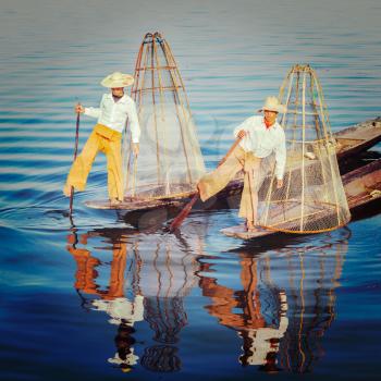 Vintage retro effect filtered hipster style image of Myanmar travel attraction. Traditional Burmese fisherman with fishing net at Inle lake famous for their distinctive one legged rowing style