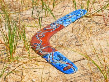 Boomerang on sand among a grass.