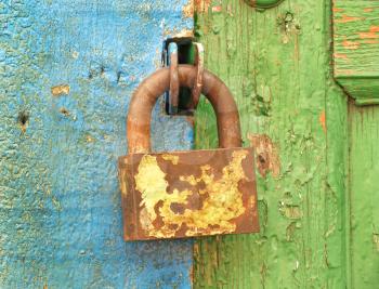 Old metal lock on a color wooden door taken closeup.