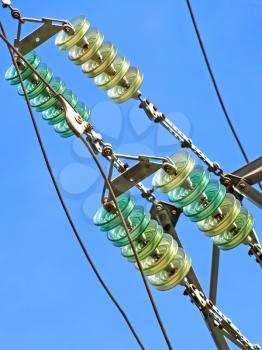 High voltage electrical insulator electric line against blue sky taken closeup.
