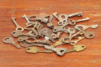 A lot of old metal keys on a wooden surface.