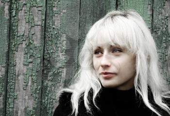 Attractive blonde against grunge green wooden wall.