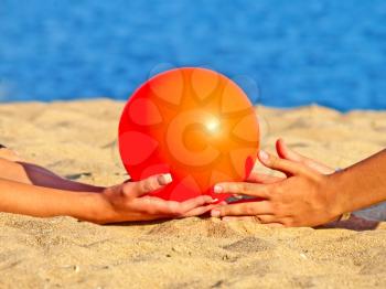 Orange ball in the women palms on beach sand.