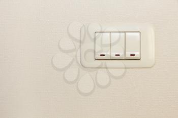 Threefold multiply light switch on white wall background.