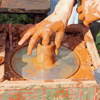 Potter makes on grunge pottery wheel clay pot.