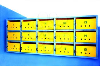 Old yellow mailboxes on white and blue wall.