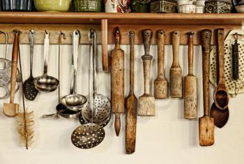 Different kitchen ware hanging on the white wall.Toned image.