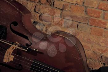 Old contrabass near brick wall.Toned image.