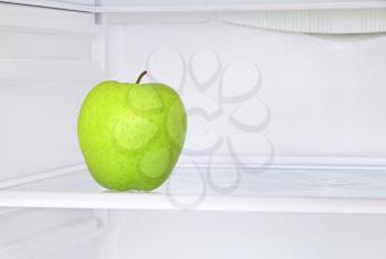 Lifestyle concept.Ripe green apple in domestic refrigerator taken closeup.