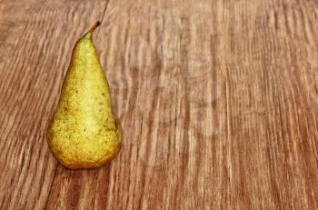 Appetizing sweet pear on grunge wooden background taken closeup.