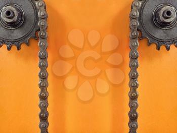 Cogwheels and double chain on orange background with empty space for text.Technology background.