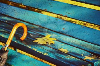 Umbrella on blue park bench taken closeup.Toned image.
