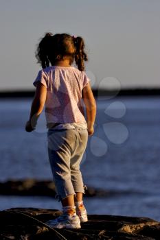 little girl on the rock in the sunrise near the  beach rio de la plata colonia del sacramento uruguay 
