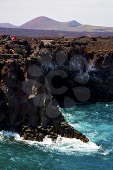 people   coastline stone volcanic spain  water  in lanzarote los hervideros sky cloud beach  and summer 
