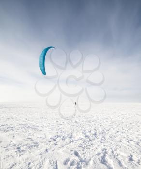 Kite surfer being pulled by his kite across the snow