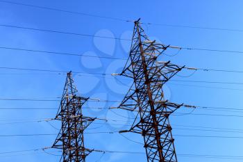 Two pillars of electric transmission lines against the blue sky